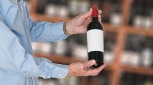 Sommelier offering bottle of red wine to customer
